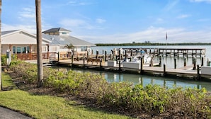 A marina with docked boats, a covered seating area, and a building with a sloped roof. - The Riverside Club - B206 (Marco Island)