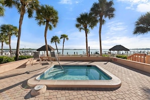 A swimming pool with a hot tub, surrounded by palm trees and a view of the water. - The Riverside Club - B206 (Marco Island)