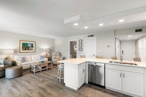 A modern kitchen with white cabinetry, a built-in dishwasher, and a large island with a sink. - The Riverside Club - B206 (Marco Island)