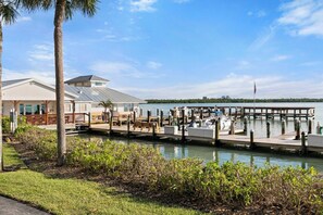 A marina with docked boats, a wooden pier, and a building with a sloped roof. - The Riverside Club - B206 (Marco Island)