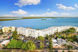 A hotel with multiple floors, a parking lot, and a view of a large body of water with islands. - The Riverside Club - B206 (Marco Island)