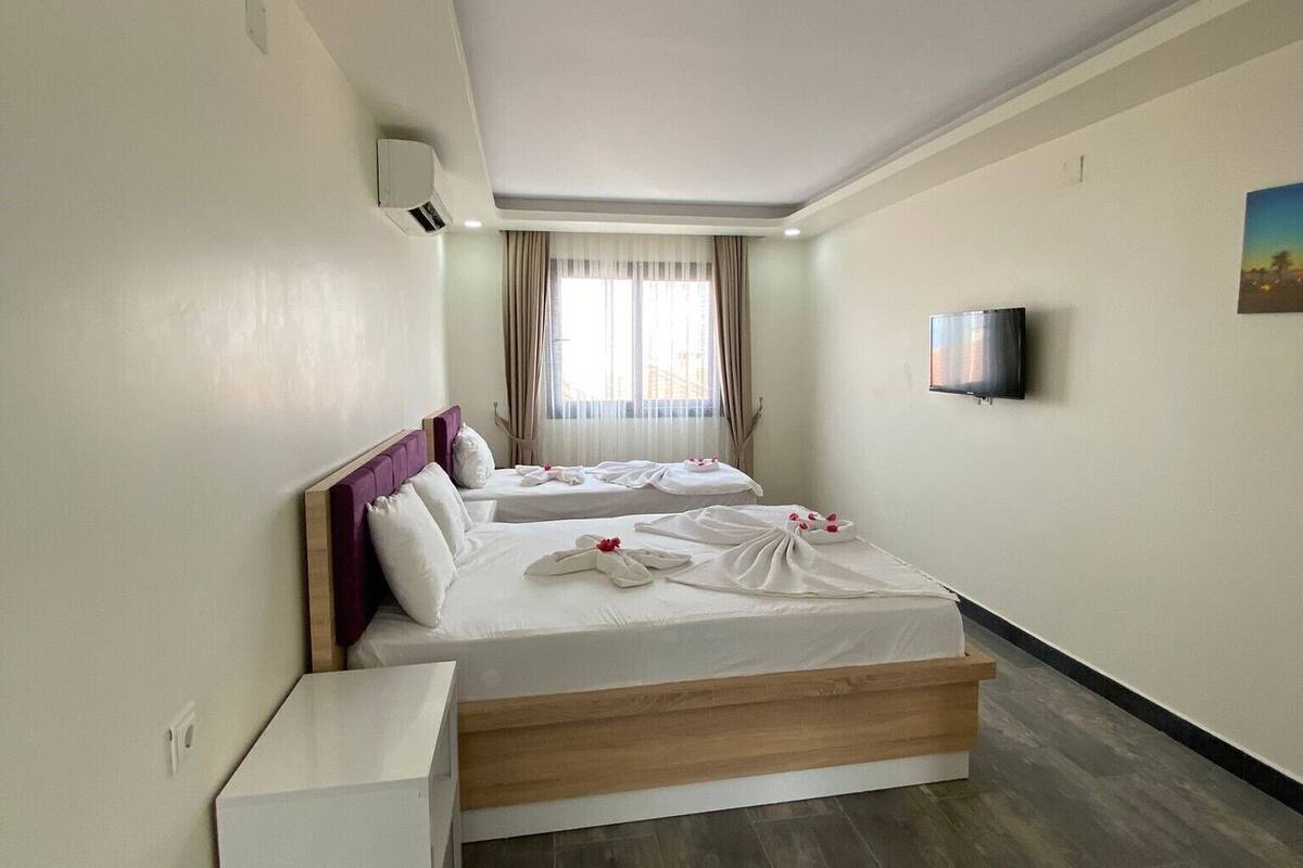 A hotel room with two beds, a TV, and a window with curtains.
