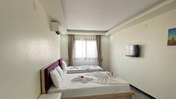 A hotel room with two beds, a TV, and a window with curtains.