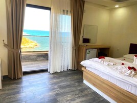 Una habitación de hotel con una cama, un escritorio pequeño, un espejo y vista al océano.