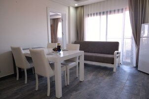 Una sala de estar moderna con una mesa de comedor y sillas, un sofá y un refrigerador.
