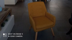 Un espace de vie moderne comprenant un coin repas, un fauteuil jaune et un espace cuisine.