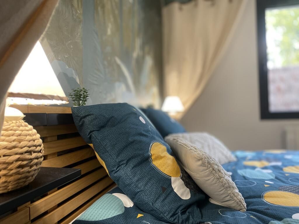 A bed with blue and white pillows, a woven basket, and a wooden headboard.