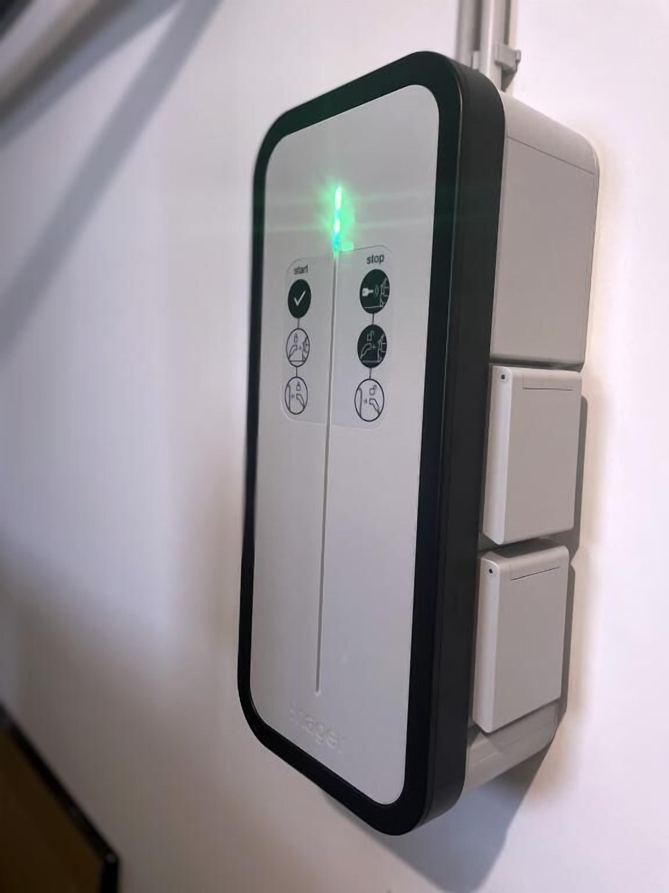 A wall-mounted control panel with a green light indicator, two buttons labeled "start" and "stop," and a small display screen.