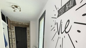 Un pasillo con una consola de madera, un espejo y una pared con la inscripción 'C'est beau la vie'.