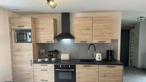Una cocina moderna con armarios de madera, horno empotrado, microondas, cafetera y hervidor.