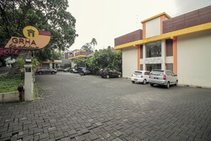 A hotel named GRHA with a signboard, a paved driveway, and parked cars.