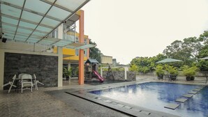 An indoor swimming pool with a slide, seating area, and a covered patio. - Collection O 295 Grha Ciumbuleuit Guest House (Bandung)