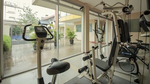 A gym with exercise equipment, large windows, and potted plants. - Collection O 295 Grha Ciumbuleuit Guest House (Bandung)