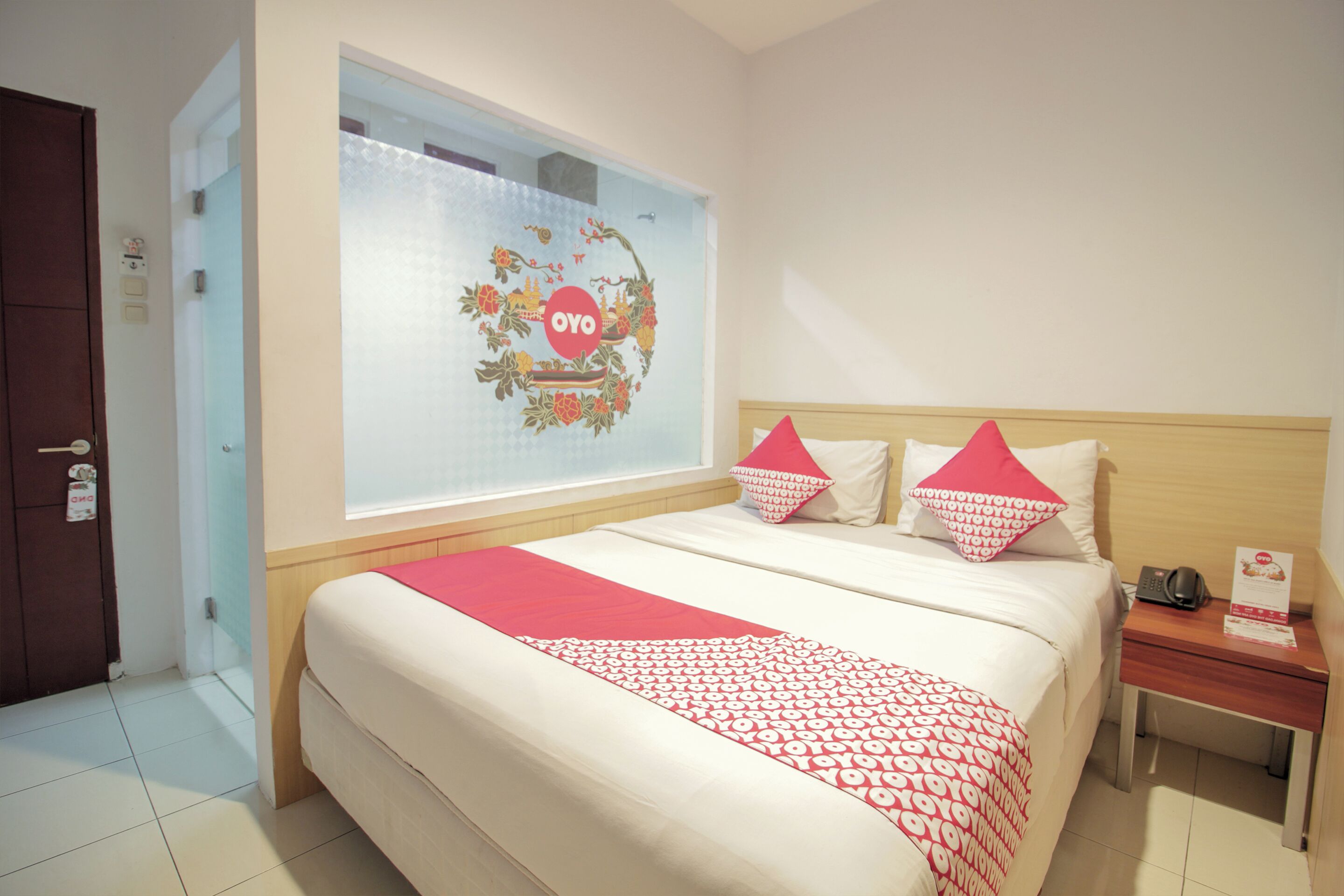 A hotel room with a large bed, a nightstand, a mirror, and a window with a decorative sticker.