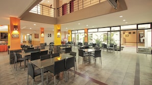 A spacious indoor area with multiple tables and chairs, a second-floor balcony, and large windows allowing natural light. - Collection O 295 Grha Ciumbuleuit Guest House (Bandung)