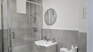 A modern bathroom with a glass shower enclosure, a white sink, and a toilet. - Lovely 2-bed Apartment in Liverpool (Liverpool)
