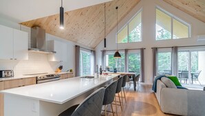 A modern kitchen with a central island, bar stools, and a dining area with a sofa. - Le Stockholm - Hot tub and Golf, Shared pool (Shannon)