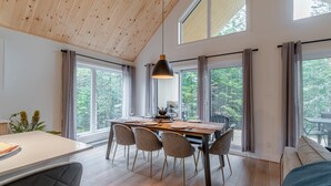 A modern dining area with a wooden ceiling, large windows, and a table set for dining. - Le Stockholm - Hot tub and Golf, Shared pool (Shannon)