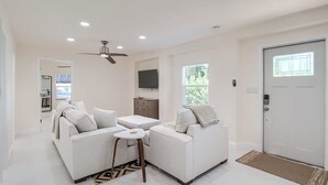 A modern living room with two sofas, a coffee table, and a ceiling fan.