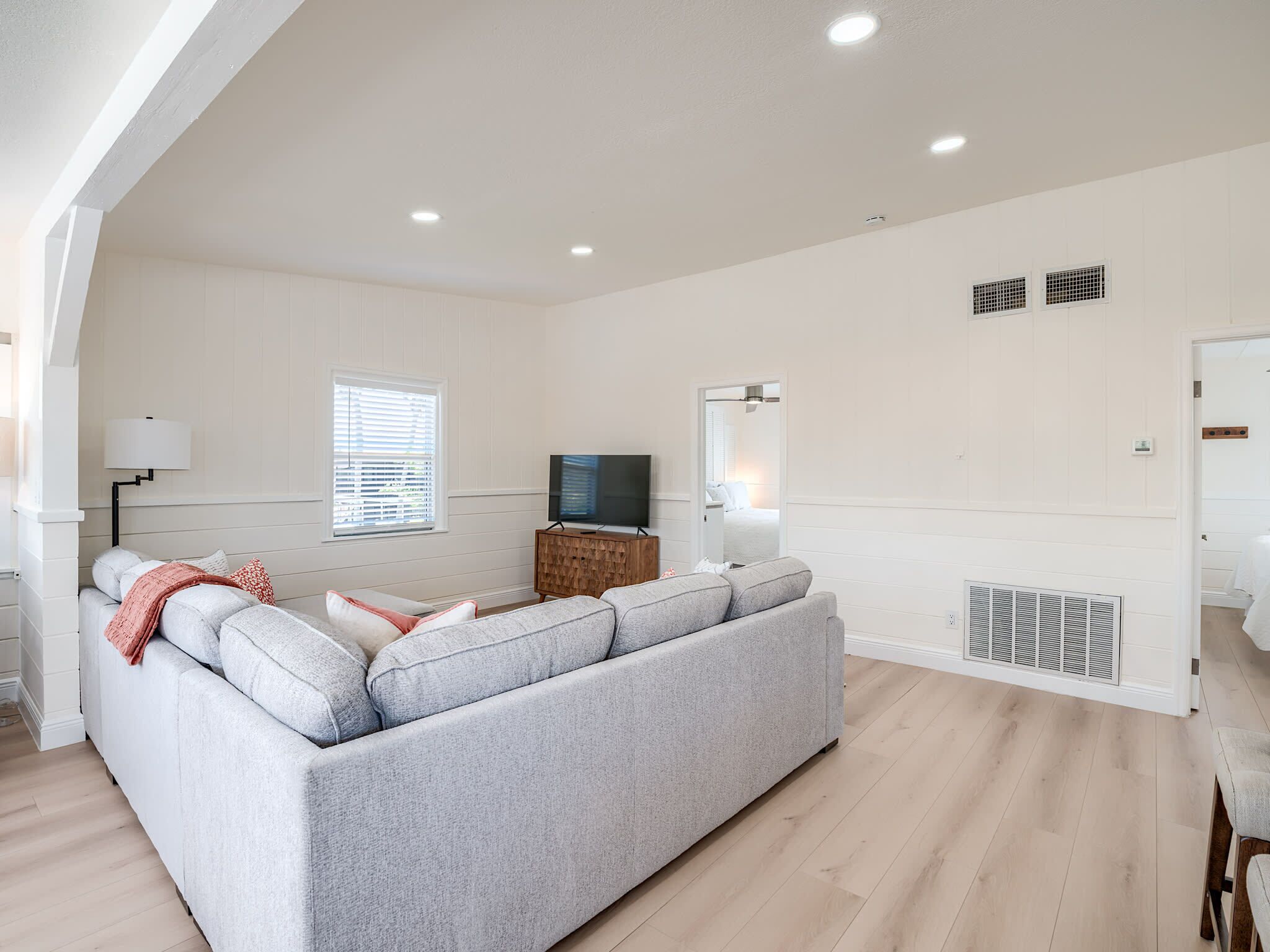 Una sala de estar moderna con un sofá seccional gris, un televisor de pantalla plana y un mueble de madera.