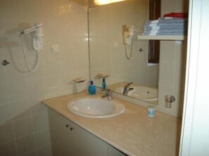 A bathroom with a sink, mirror, and towel rack.