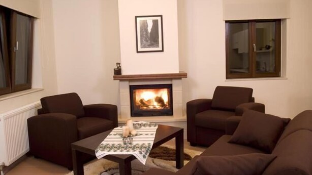 A living room with a fireplace, two sofas, a coffee table, and a window with blinds. - Your Gorge-side Getaway Modern Villas, Natural Beauty (Platanias)