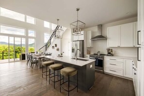 Cozinha moderna com uma ilha grande, banquetas, escada e vista para o exterior.