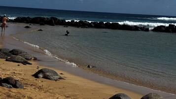 A beach with sand, rocks, and the ocean.