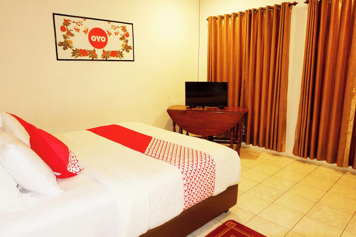 A hotel room with a bed, a TV on a wooden table, and curtains.