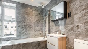 A modern bathroom with a bathtub, a shower, and a vanity with a mirror.