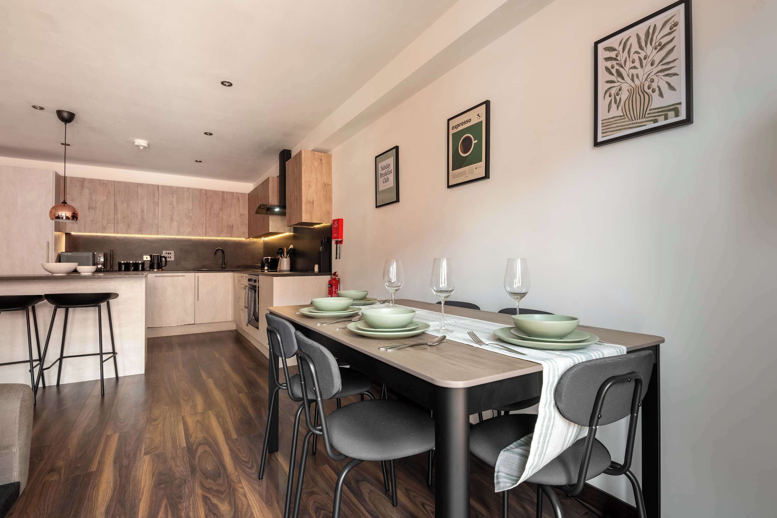 A modern kitchen with a dining area, wooden flooring, and a bar counter.