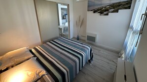 Une chambre à coucher comprenant un lit, une fenêtre, un miroir et une œuvre d’art accrochée au mur.
