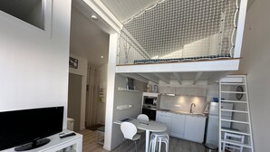 Un espace de vie compact comprenant un coin cuisine, un coin repas et un téléviseur posé sur un meuble.