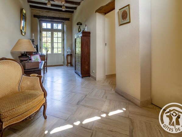A spacious room with a wooden floor, a large wooden cabinet, a wicker chair, and a table with a lamp. - Charming Stay with Pool in Loire Valley's Wine Region (Doué-en-Anjou)