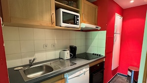 Eine kompakte Küche mit Mikrowelle, Toaster, Spüle, Geschirrspüler und einem kleinen Backofen.