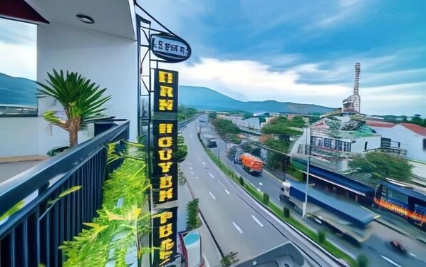 Une enseigne d’hôtel avec une vue sur un paysage urbain, comprenant une autoroute et des montagnes.