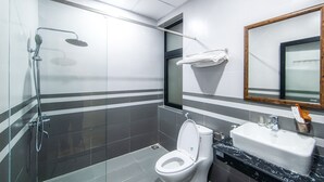Un baño moderno con ducha de vidrio, inodoro blanco y lavamanos con espejo.