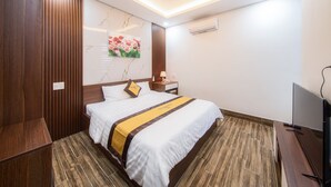 Una habitación de hotel con una cama, una mesita de noche, un televisor y un cuadro en la pared.