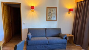 Ein Wohnzimmer mit einer Couch, einem kleinen Tisch und einem gerahmten Bild an der Wand.