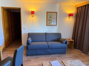 Een woonkamer met een bank, een bijzettafeltje en een lijst met een foto aan de muur.