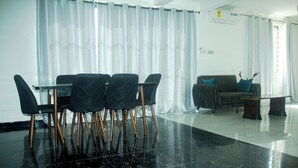 A modern living room with a dining area, featuring a glass table, black chairs, a sofa, and a coffee table. - Exclusive Villa - 5str Hideout, Private Pool, Wifi (Accra)