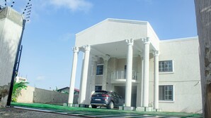 A building with a covered entrance, columns, and a car parked in front. - Exclusive Villa - 5str Hideout, Private Pool, Wifi (Accra)
