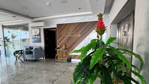 A hotel lobby with a marble floor, a reception desk, a large potted plant, and a framed artwork on the wall. - Rose Land Hotel (Umluj)