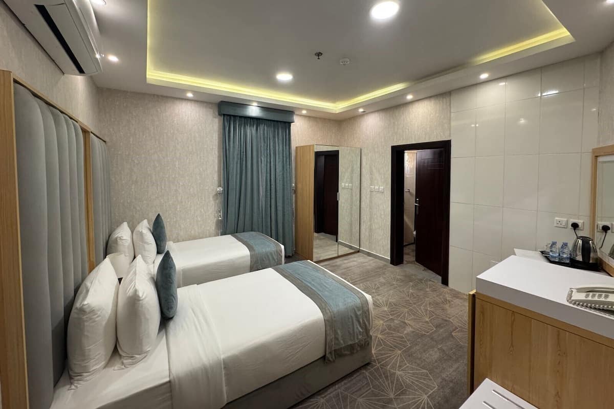 A hotel room with two beds, a bathroom, and a desk with a mirror.
