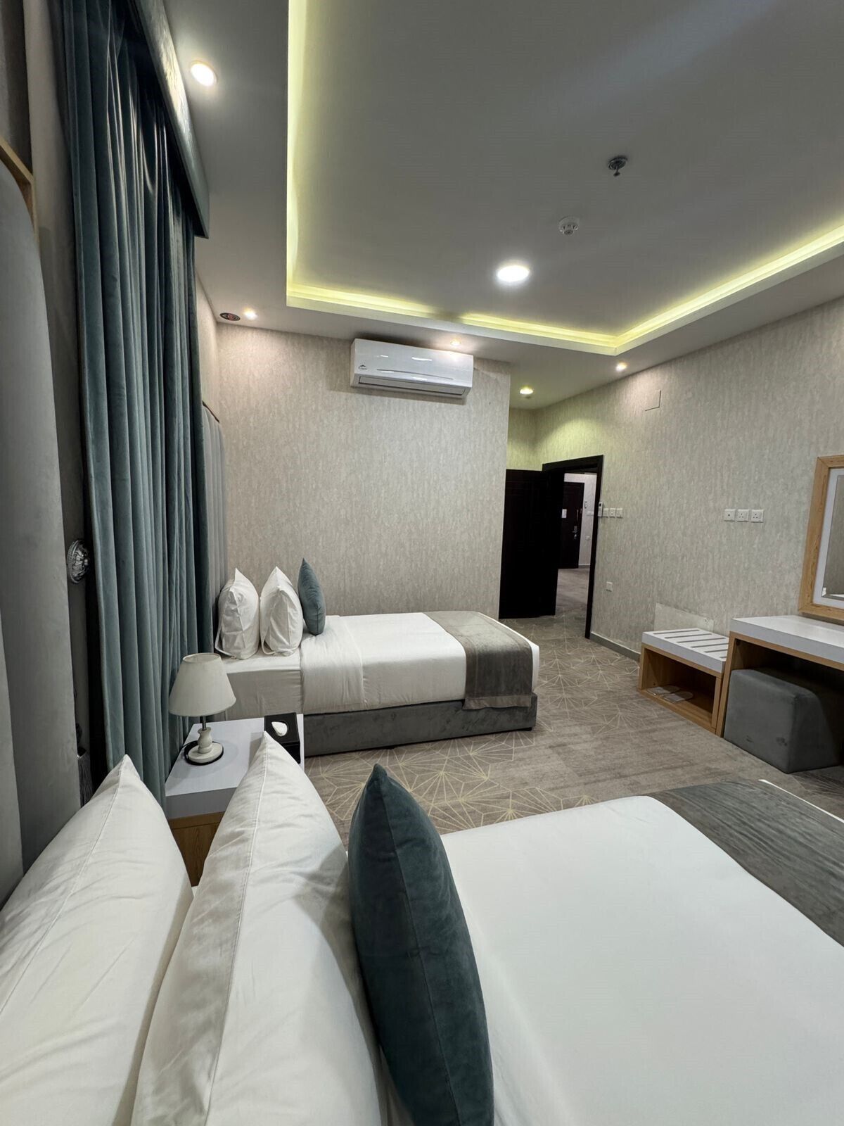 Une chambre d’hôtel moderne équipée d’un lit, d’une table de chevet, d’une lampe et d’un appareil de climatisation.