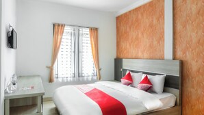 Una habitación de hotel moderna con una cama grande, un cabecero de madera y un escritorio pequeño con una silla.