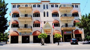 A multi-story hotel with balconies, a travel agency sign, and a cafe. - Alpine hotel  (Qabr Chamoun)