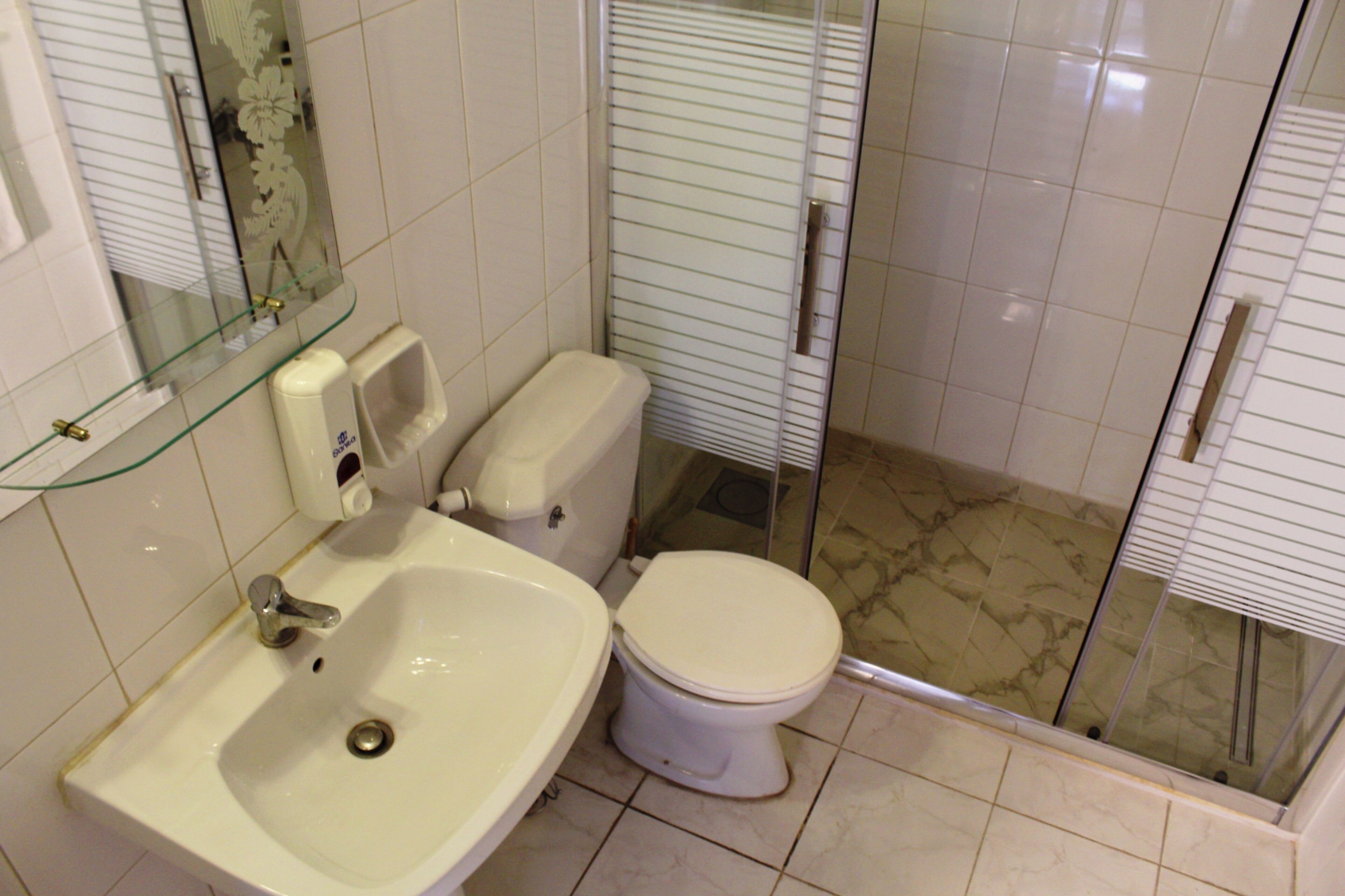 Un baño con lavamanos, inodoro y cabina de ducha de vidrio.