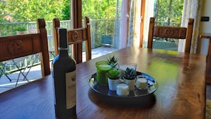 Une table en bois, une bouteille de vin Barbera, un plateau avec de petits verres et des plantes succulentes.