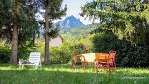 A table and chairs in a grassy area with a mountain in the background. - Villa with outbuildings close to the lake and shops. (Savines-le-Lac)